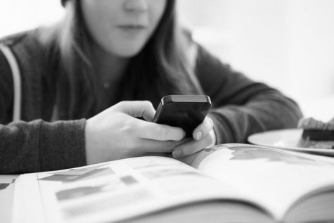 A teenager uses a cell phone in class.