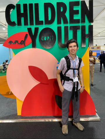 Manolo Avalos standing in front of a sign designating a zone for children and youth at COP27.