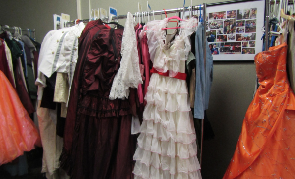 Cinderella costumes on a clothing rack backstage.