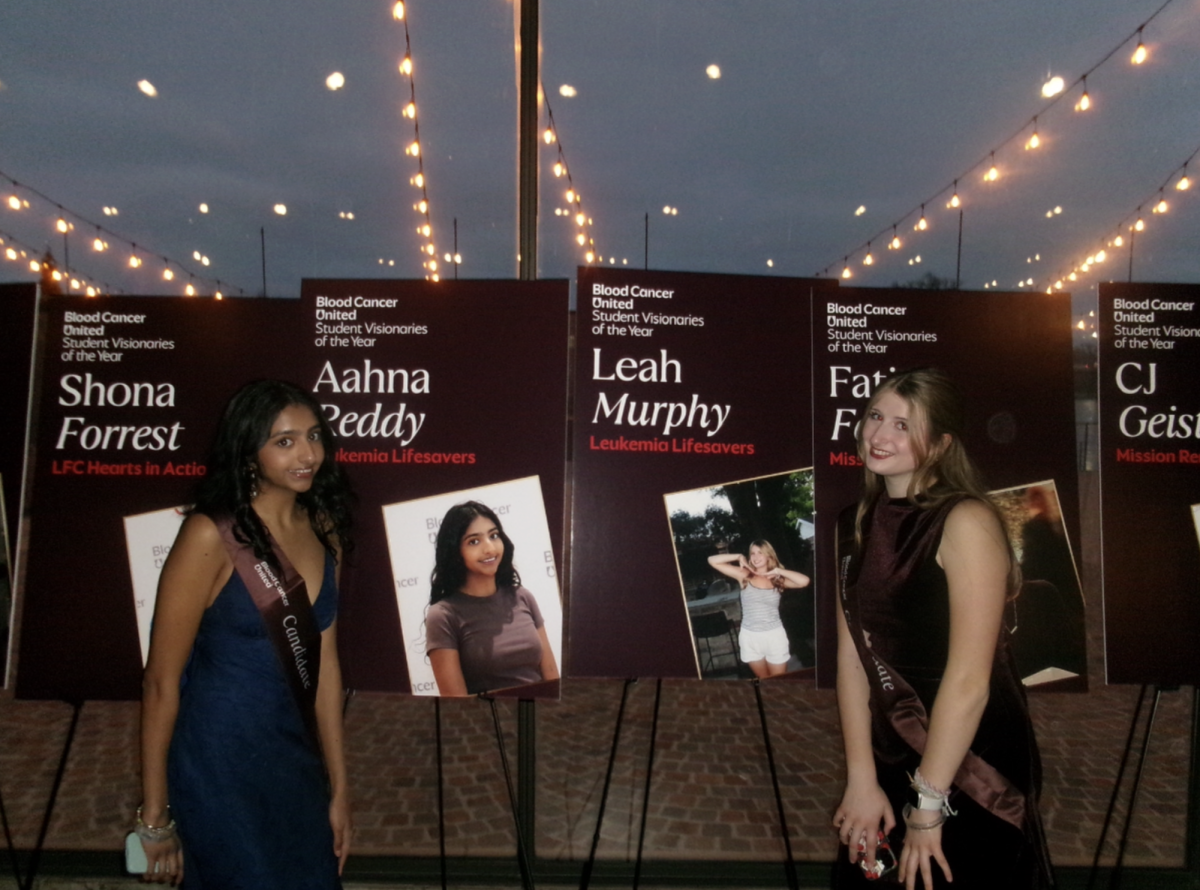 Aahna Reddy and Leah Murphy pose in front of Leukemia Lifesavers posterboards
